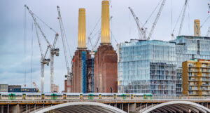 A photo of Battersea Power Station, London, surrounded by cranes with a railway bridge in the foreground.