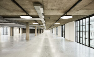 A perspective interior view of the industrial-style Wenlock Works building in Old Street, London, with slate-grey concrete pillars.